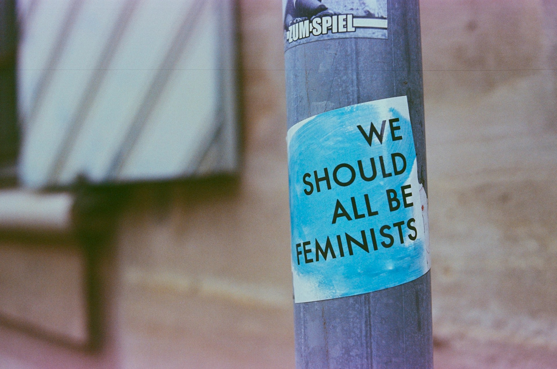 Roadsign pole with sticker that has text we should all be feminists