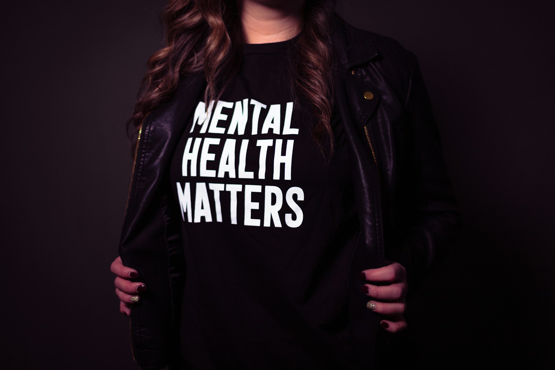 A woman torso wearing black jacket and black tshirt with white text mental health matters